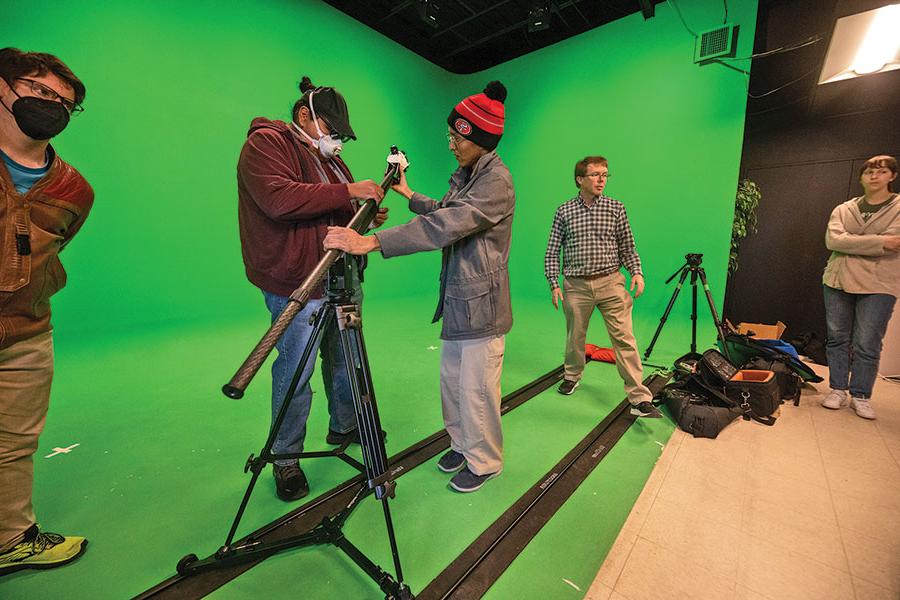 Students getting video equipment together in front of a green screen